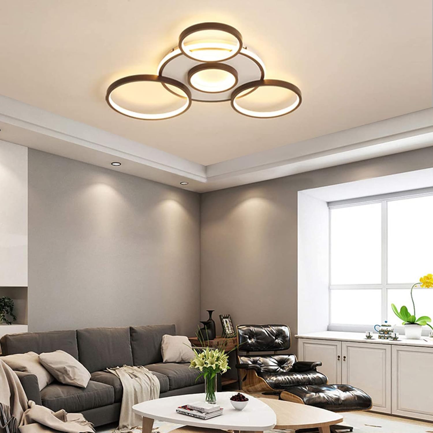 Modern living room with a ceiling light fixture, gray sofa, and black leather chair.