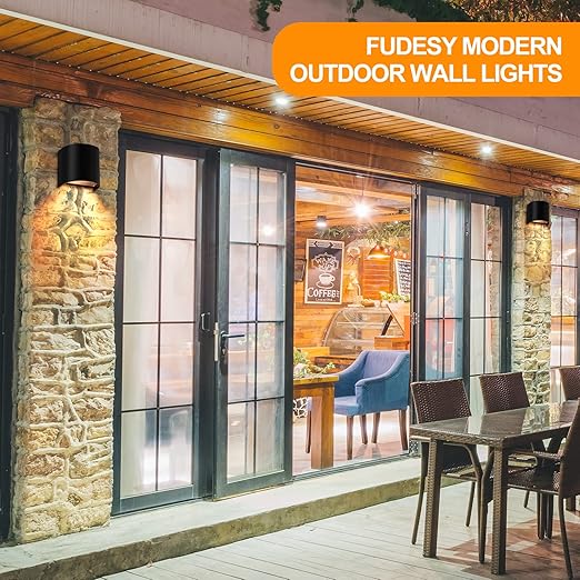Modern outdoor wall lights on a stone wall with a patio and dining area in the background.