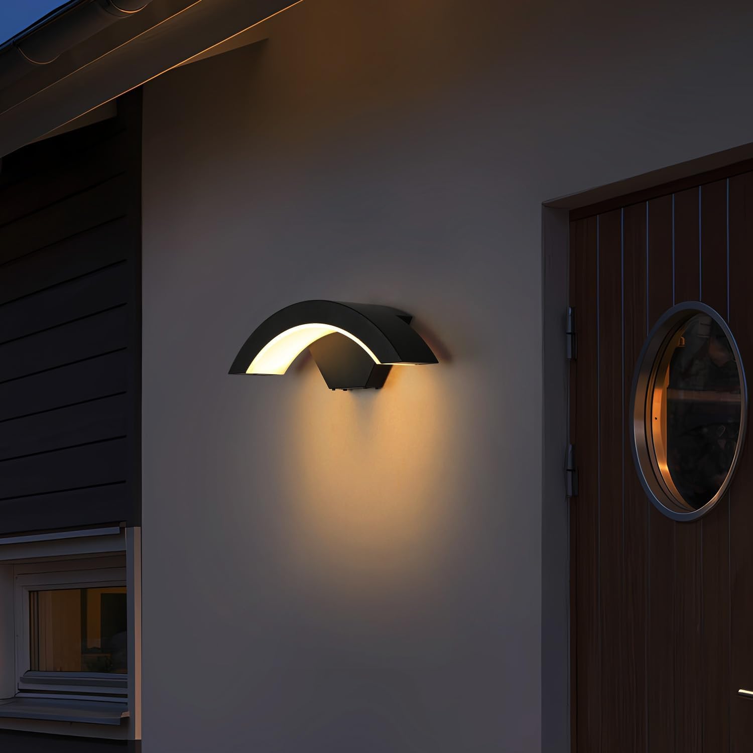Modern outdoor wall light fixture on a house exterior at night.
