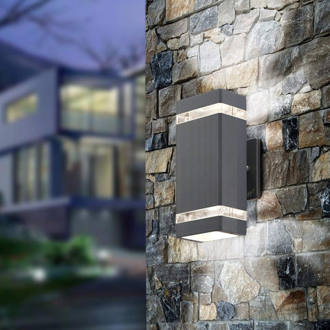Modern outdoor wall light fixture on a stone wall with a blurred building in the background