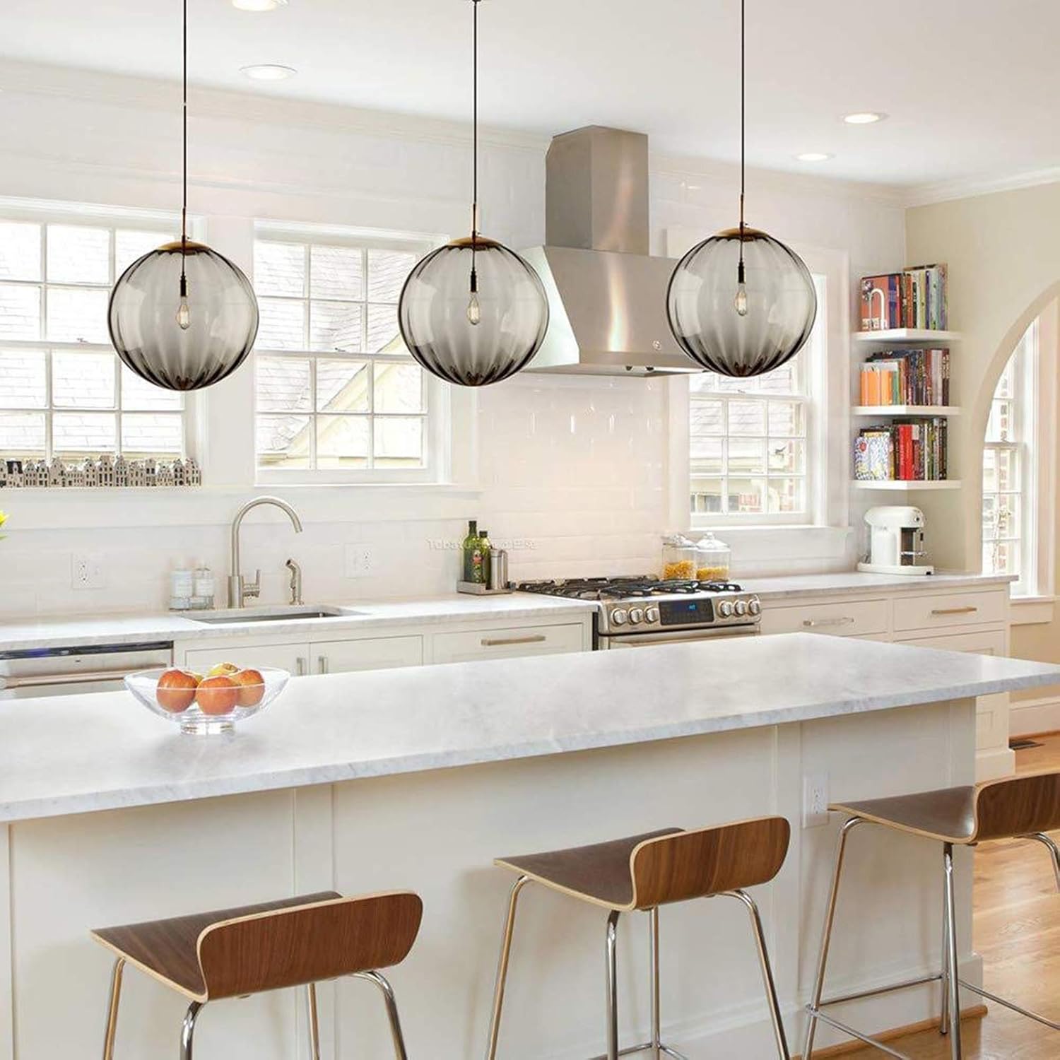 Modern pendant light fixture with three glass shades and gold accents on a white background