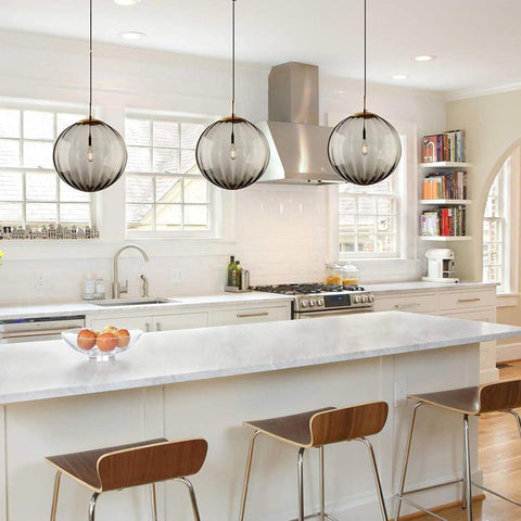 Modern pendant light fixture with three glass shades and gold accents on a white background