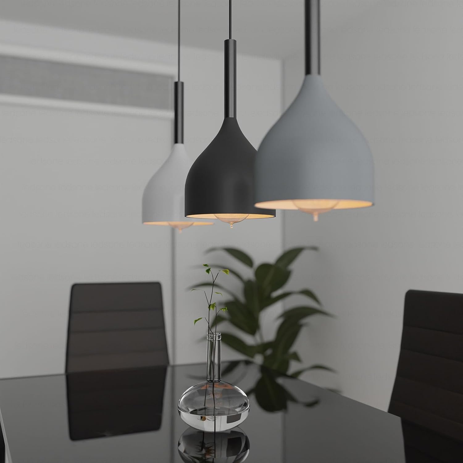 Modern pendant lights hanging above a dining table with chairs and a plant in the background.