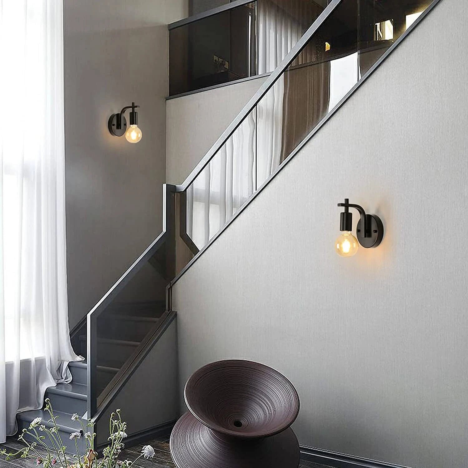 Modern staircase with wall lights and a decorative bowl in a home interior.