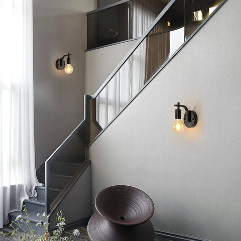 Modern staircase with wall lights and a decorative bowl in a home interior.