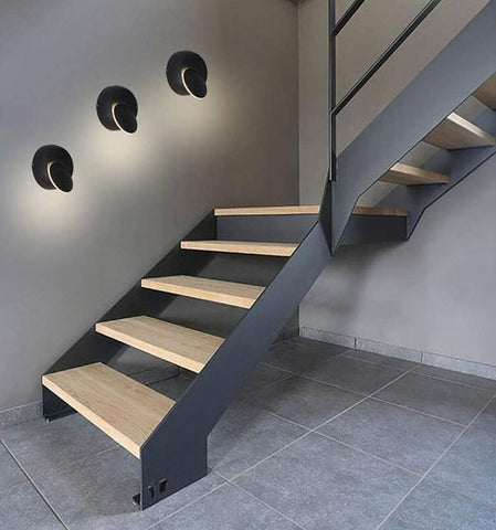 Modern staircase with wooden steps and metal railings in a gray room.