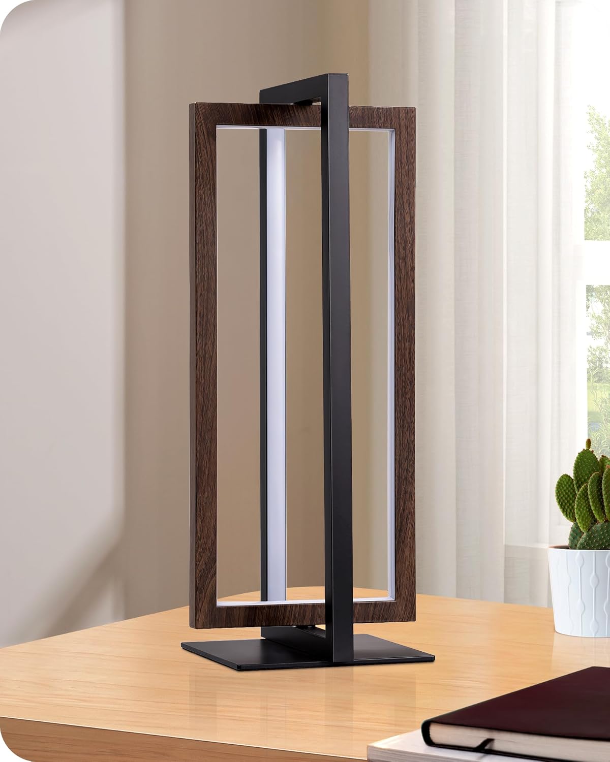 Modern table lamp with wooden frame on a desk next to a plant and books