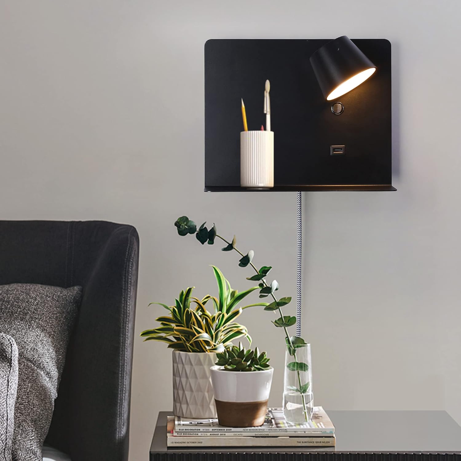 Modern wall-mounted lamp with a candle and decorative plants on a table.