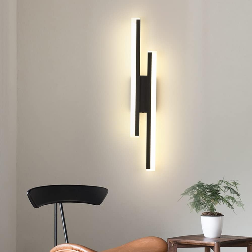Modern wall-mounted light fixture on a neutral wall with a chair and plant in the foreground.