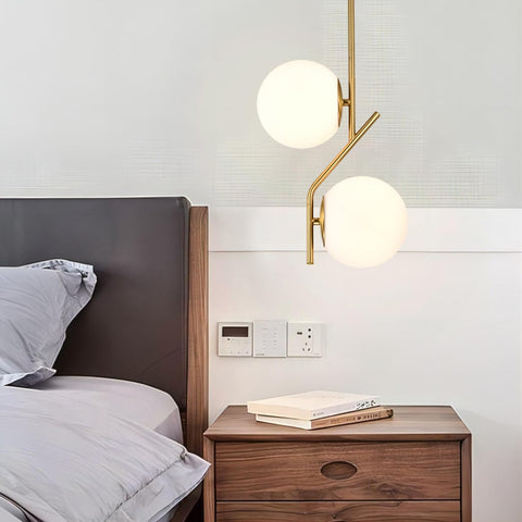 Modern wall lamp with spherical glass shades in a bedroom setting.