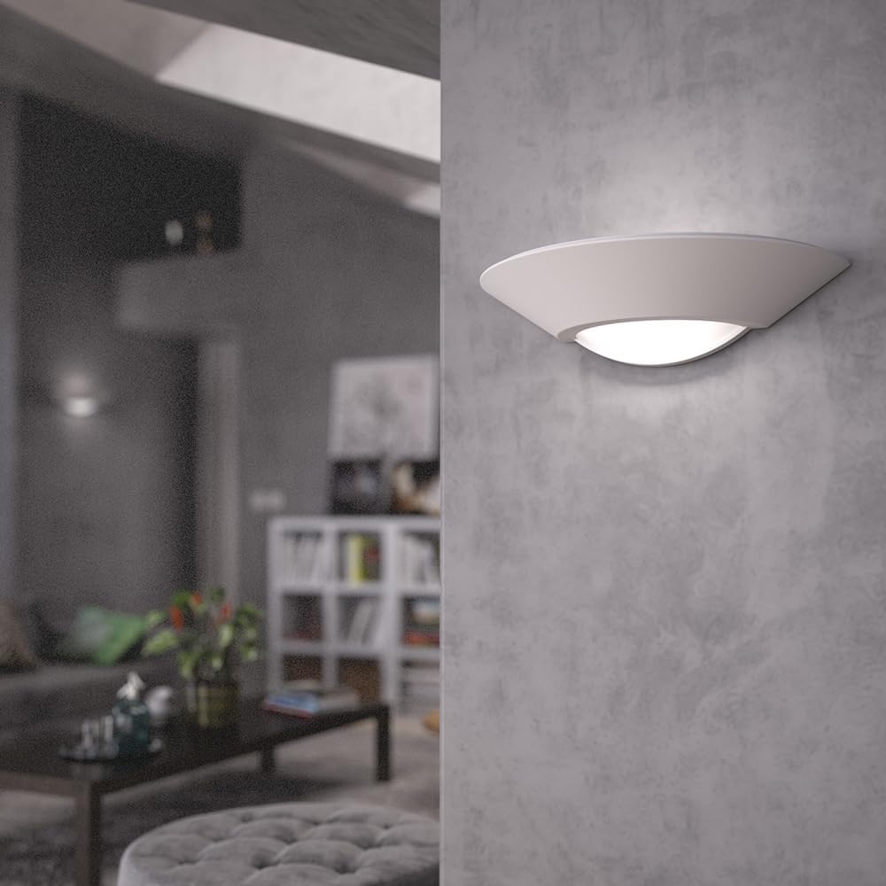 Modern wall light fixture on a gray wall with a blurred living room in the background