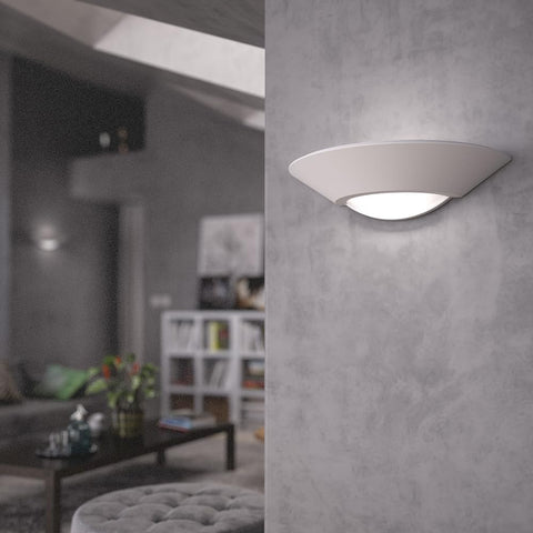 Modern wall light fixture on a gray wall with a blurred living room in the background