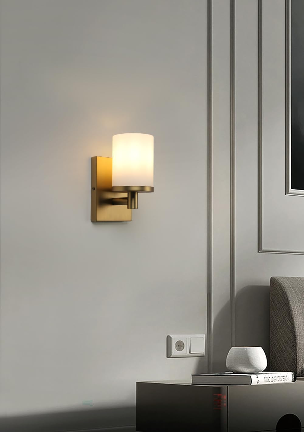 Modern wall sconce on a gray wall with a side table and framed picture in the background.