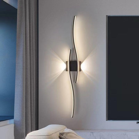 Modern wall sconce on a neutral wall with a television in the background