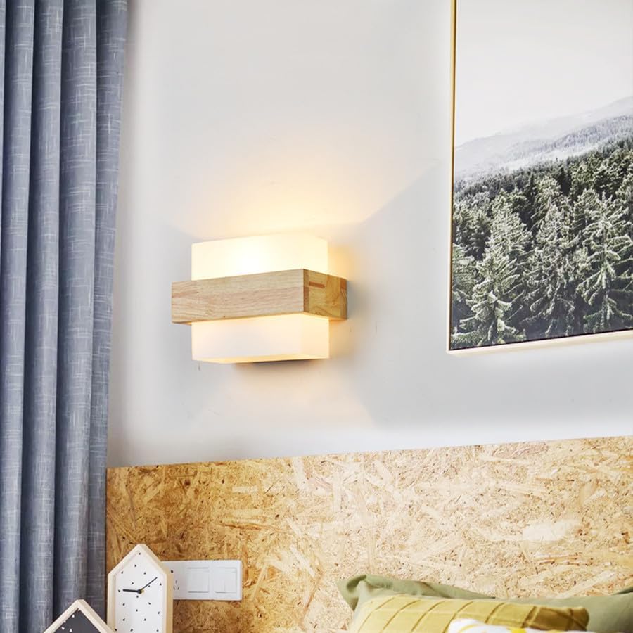 Modern wall sconce on a wall with a decorative headboard and framed picture.