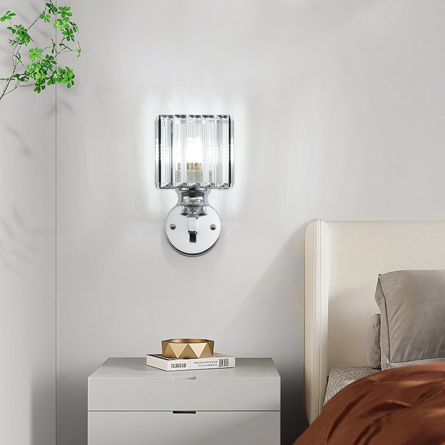 Modern wall sconce on a white wall above a nightstand with a book and decorative bowl.