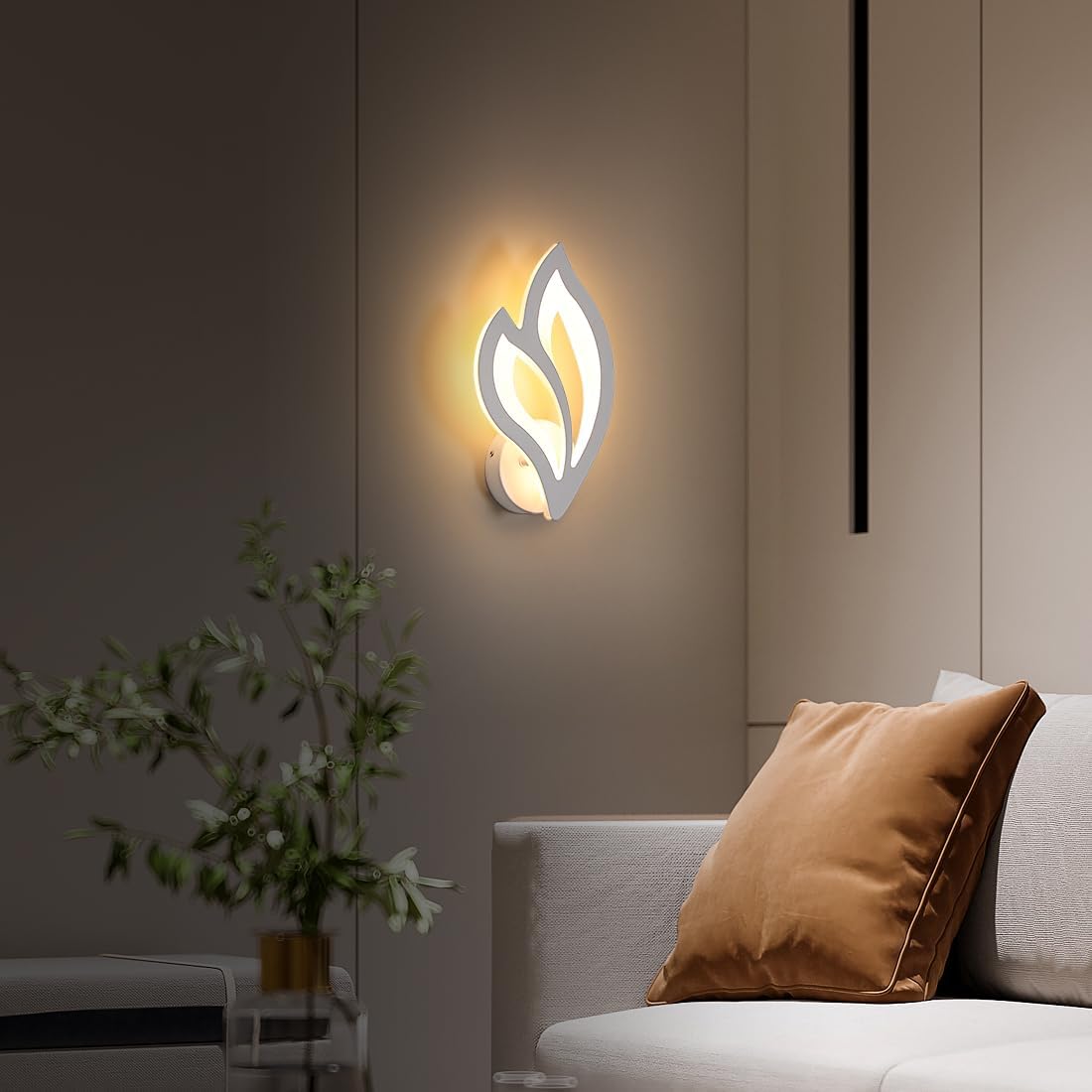 Modern wall sconce with leaf design on a neutral wall in a living room setting.