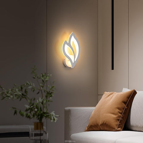 Modern wall sconce with leaf design on a neutral wall in a living room setting.
