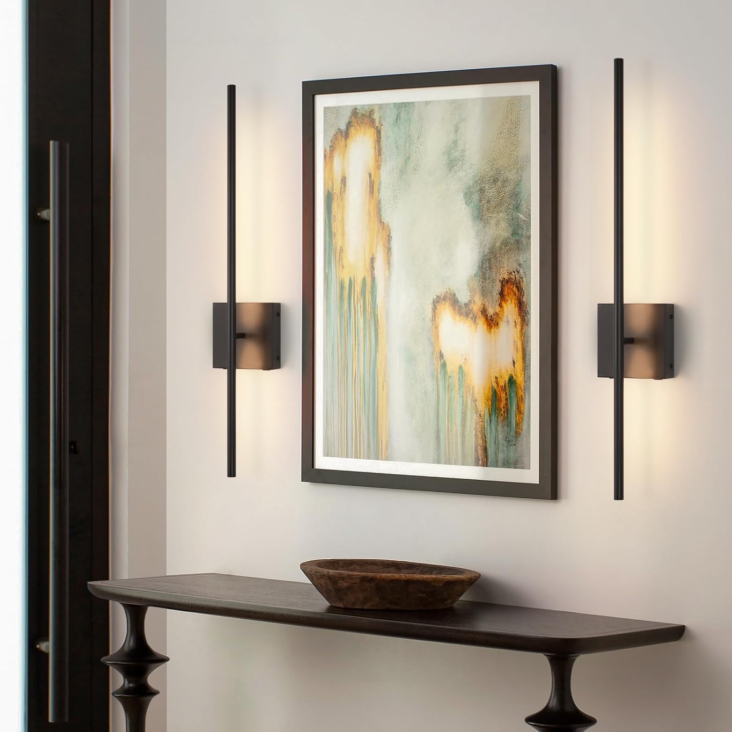 Modern wall sconces flanking a framed abstract painting in a room with a console table.