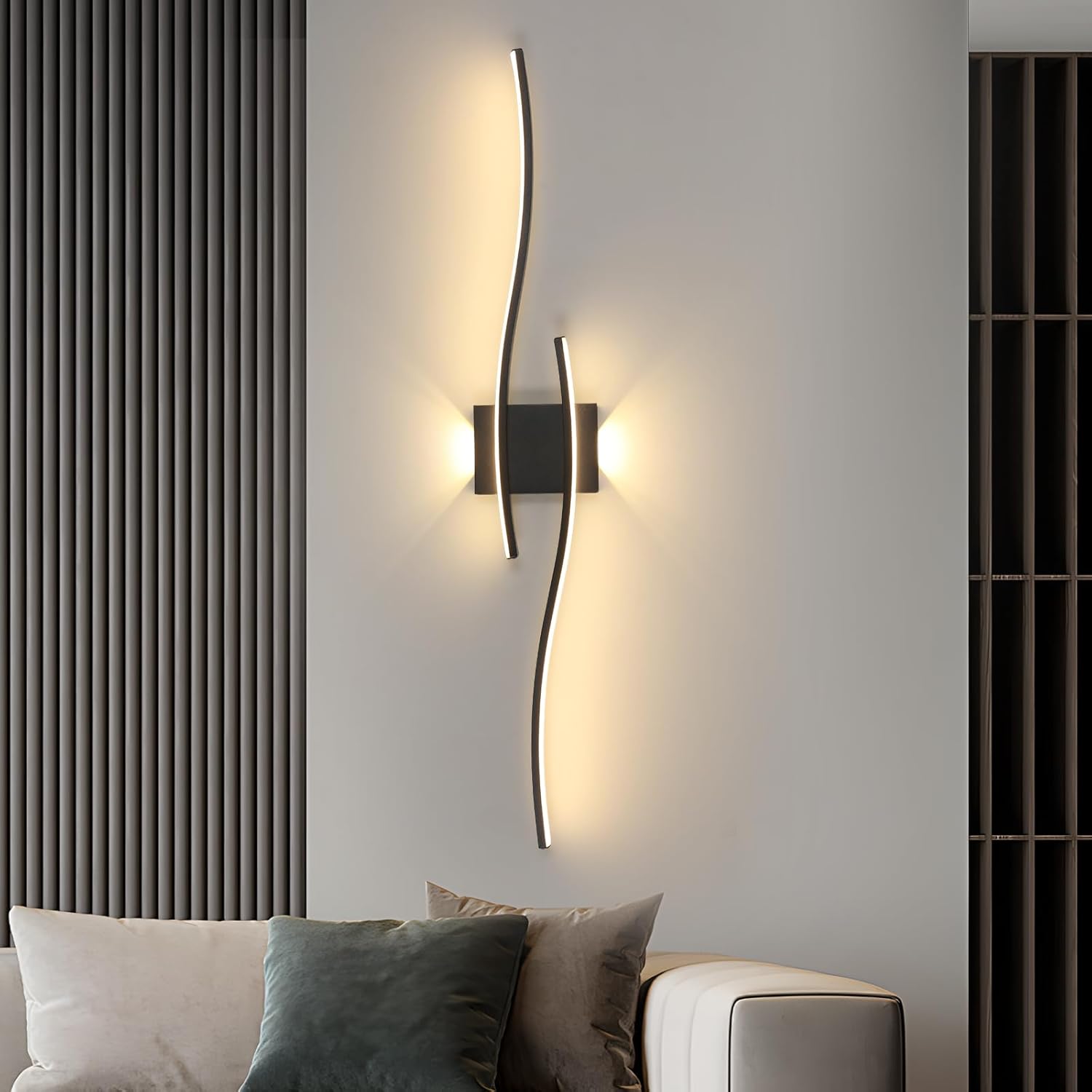 Modern wall sconces on a gray wall with a sofa and decorative pillows in the foreground.