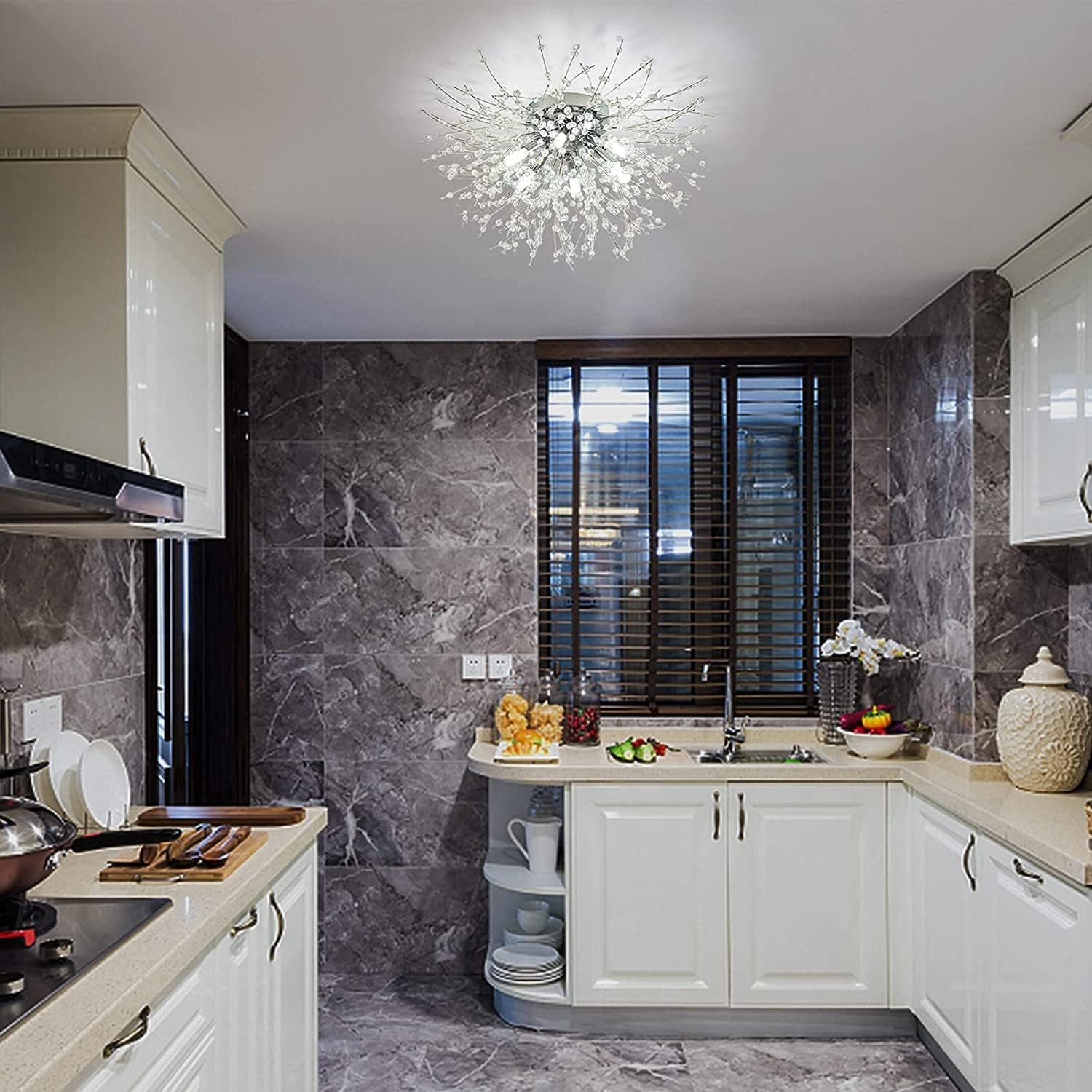 Modern kitchen with marble walls, white cabinets, and a chandelier.