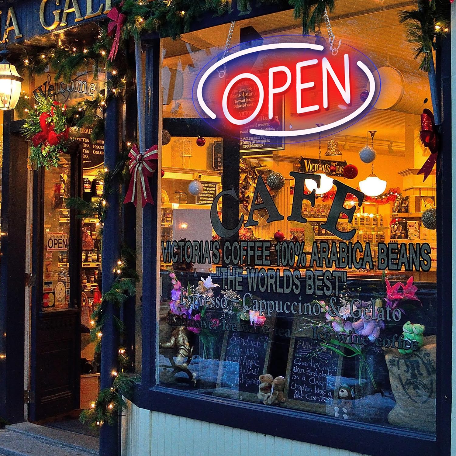 Neon 'OPEN' sign above a cafe window with Christmas decorations.