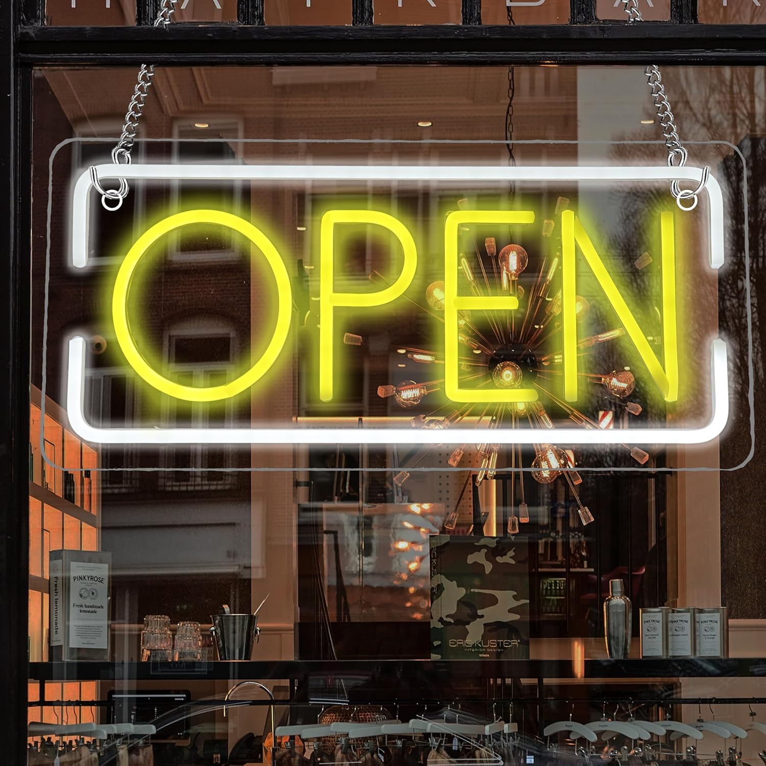 Neon 'OPEN' sign in a store window with interior reflections.