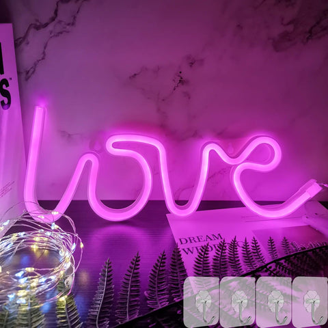 Neon sign spelling 'LOVE' on a marble surface with decorative elements.
