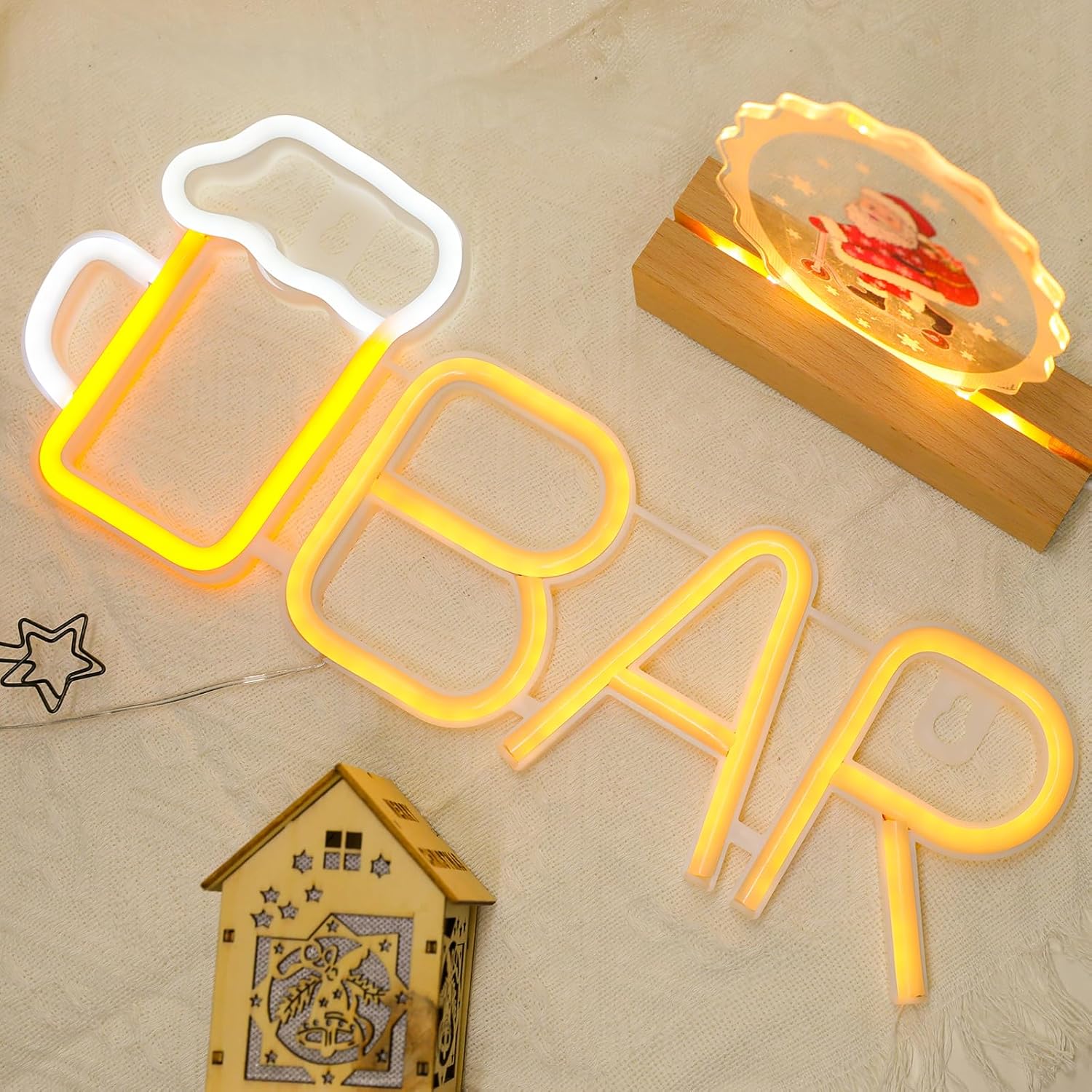 Neon sign with 'BAR' and a small wooden house decoration on a beige surface.