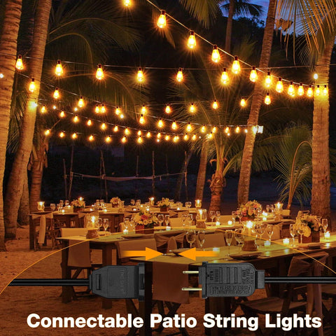 Outdoor dining setup with string lights under palm trees at night.