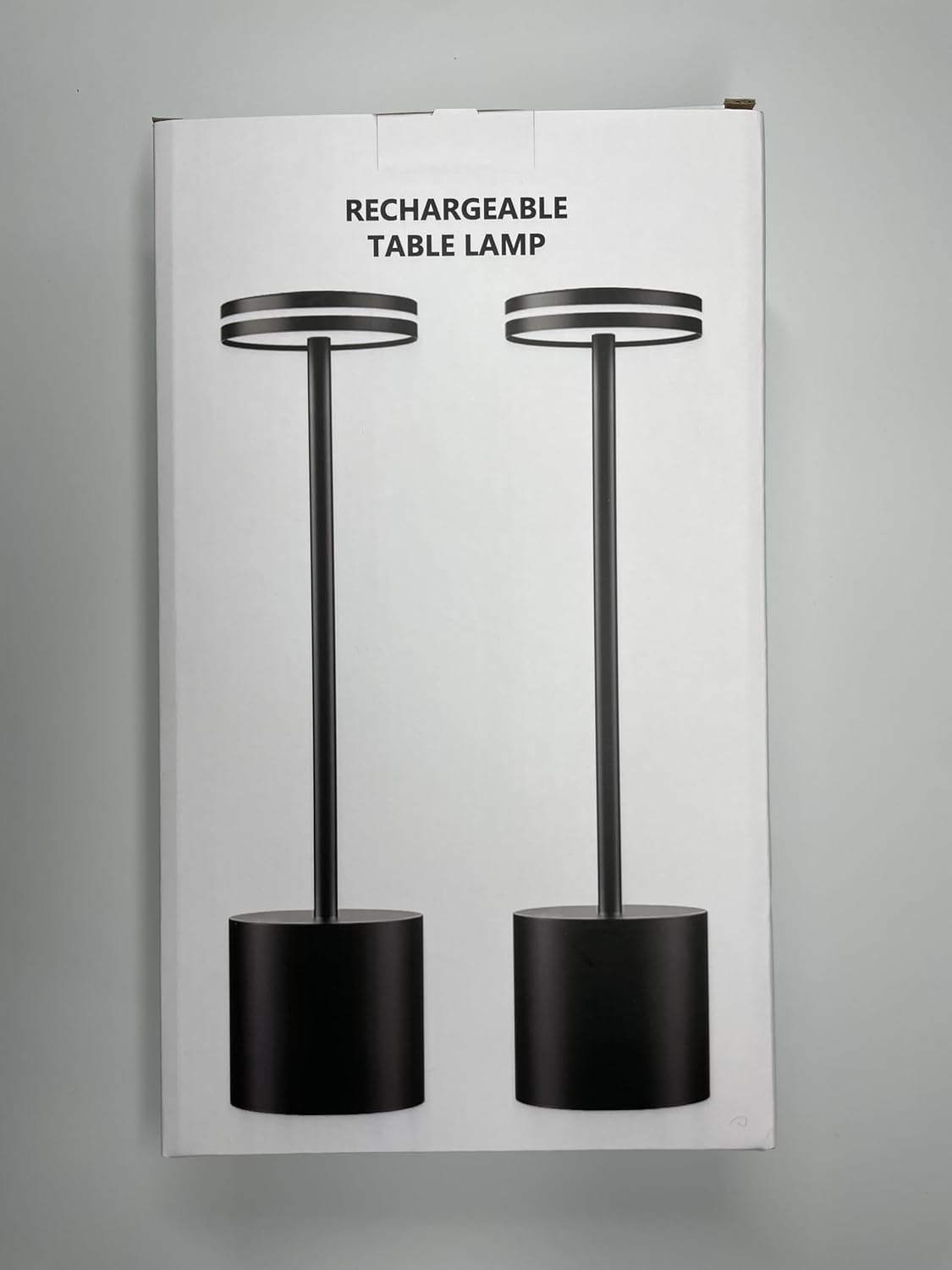 Packaging of a rechargeable table lamp with black design on a gray background