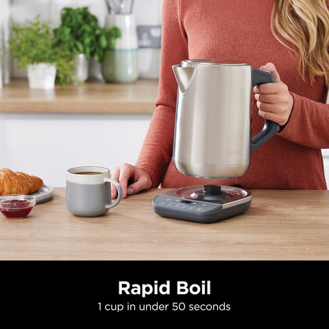 Person holding a electric kettle with a cup of coffee on a kitchen counter, featuring the text 'Rapid Boil'.