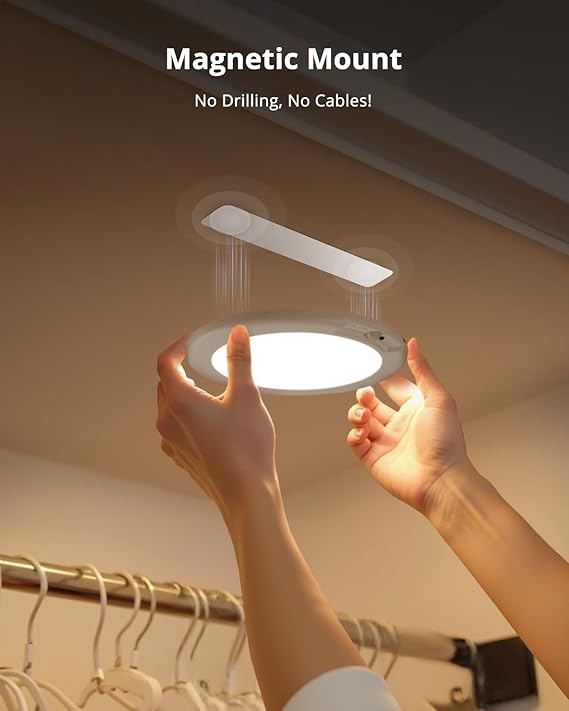 Person holding a light fixture with a magnetic mount feature in a closet setting.
