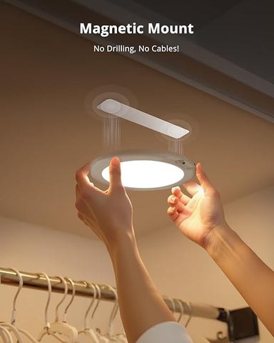 Person holding a light fixture with a magnetic mount feature in a closet setting.