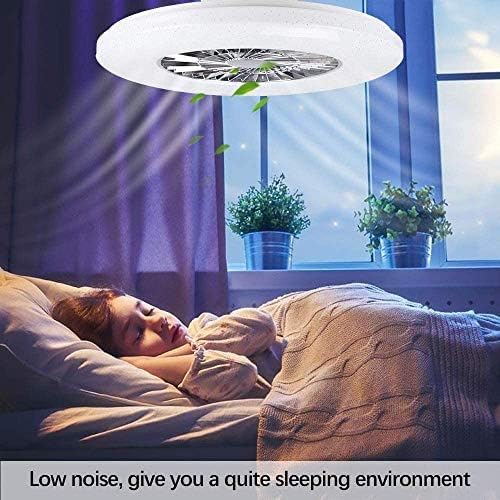 Person sleeping in a bedroom with a ceiling fan above them, plants in the background.