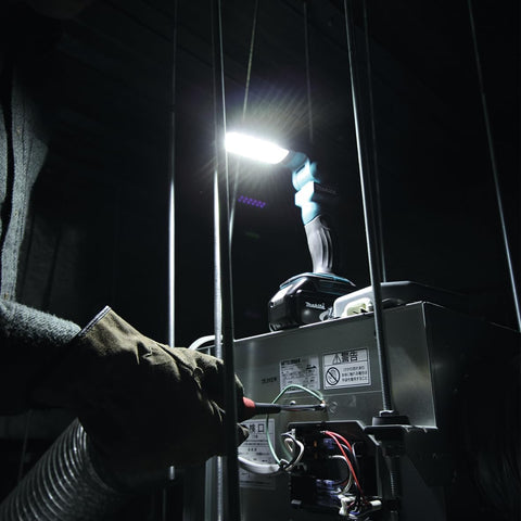 Person using a flashlight to inspect equipment in a dark setting