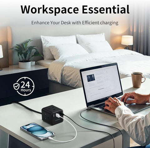 Person using a laptop on a desk with a power adapter and phone, bedroom in the background