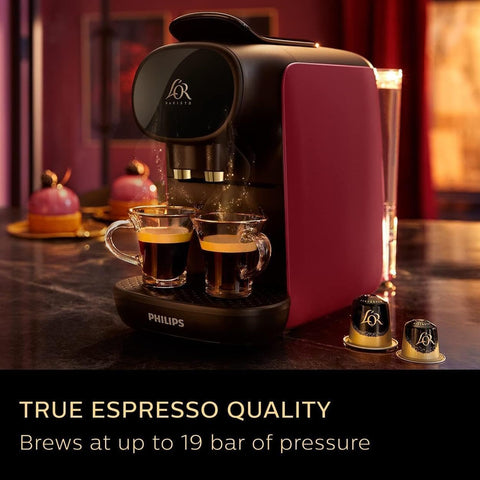 Philips coffee machine brewing espresso with two cups on a dark surface.