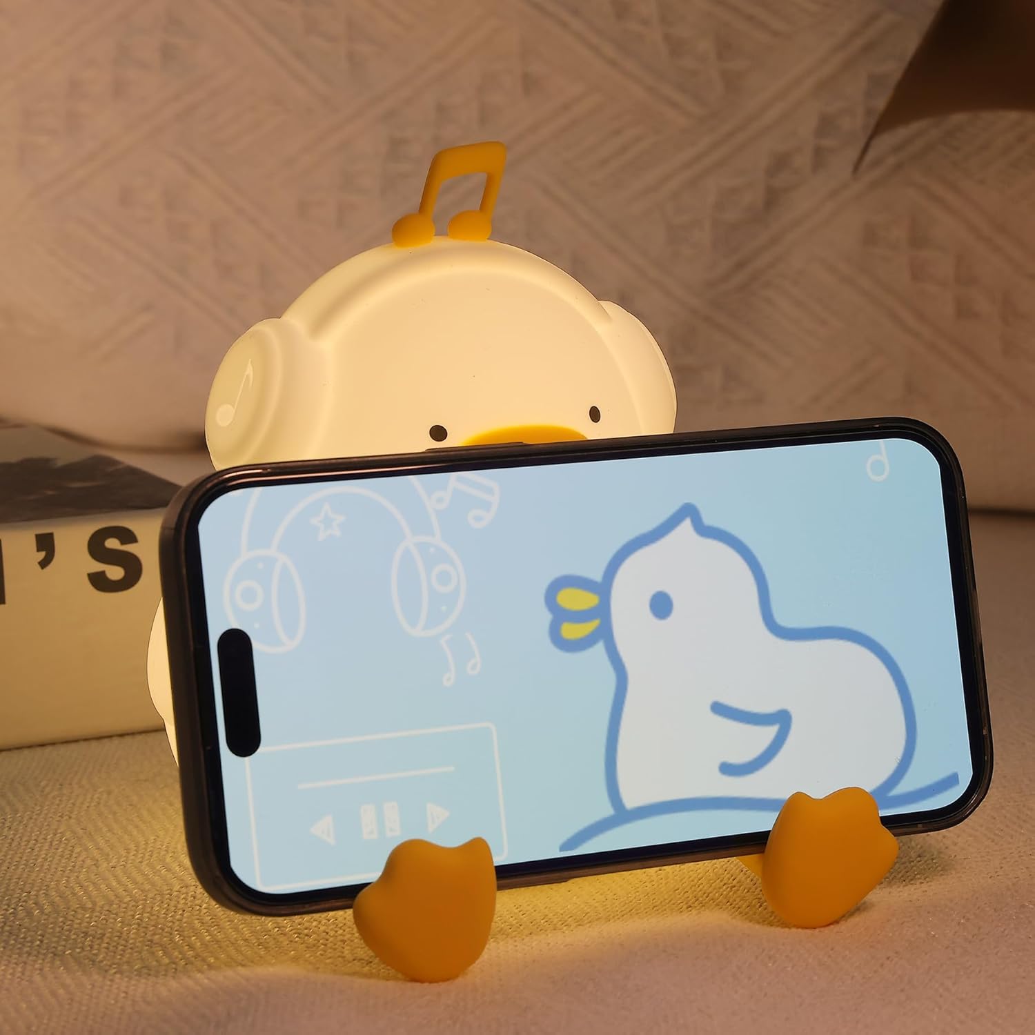 Phone holder shaped like a duck with a phone displaying a cartoon duck on a textured surface.