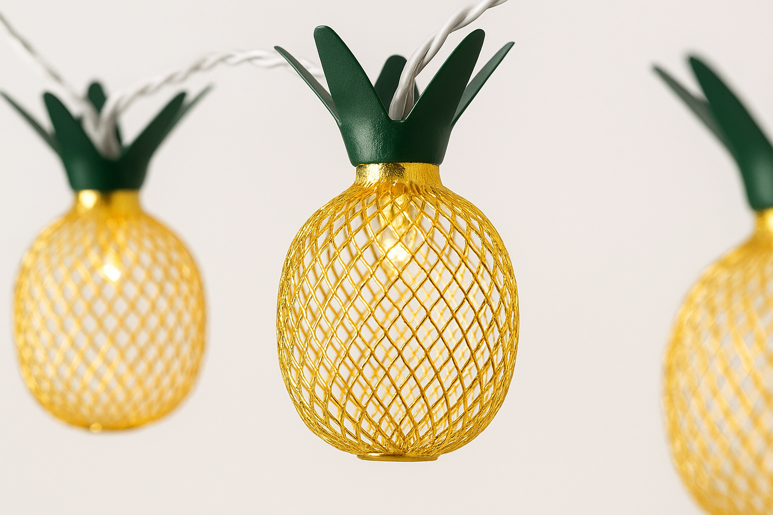Pineapple-shaped string lights with green tops on a white background