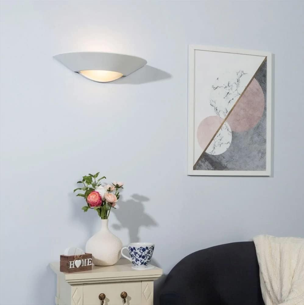 Room interior with a vase of flowers, a cup, and a framed abstract painting on a light blue wall.