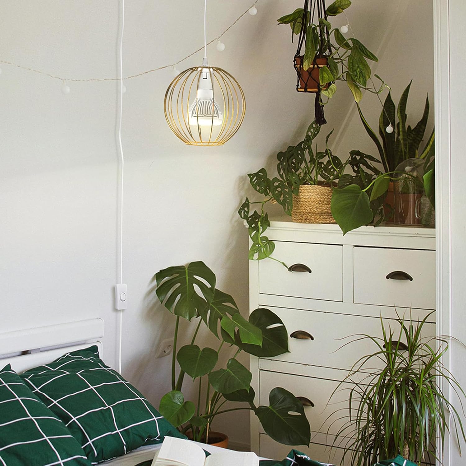 Room interior with a white dresser, green plants, and a hanging light fixture.