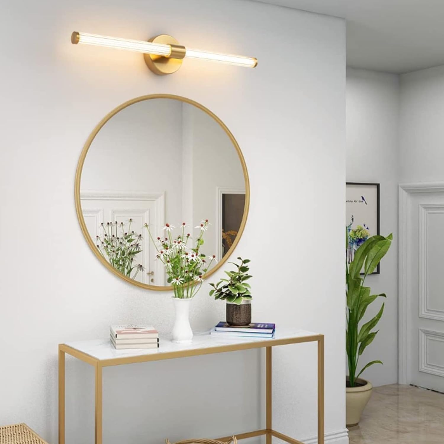 Round gold-framed mirror on a white wall above a small table with decor items.
