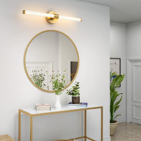 Round gold-framed mirror on a white wall above a small table with decor items.