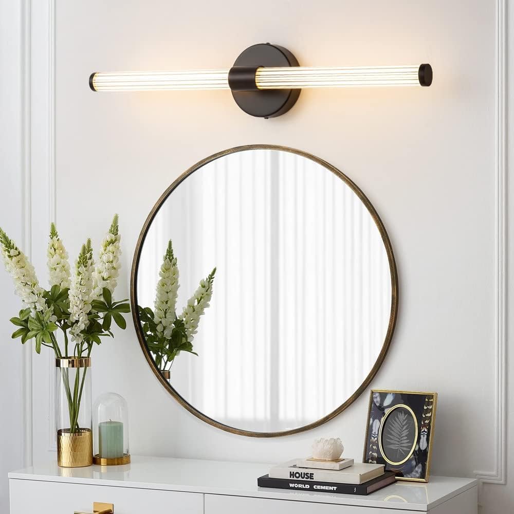 Round mirror with a modern wall light fixture on a white wall.