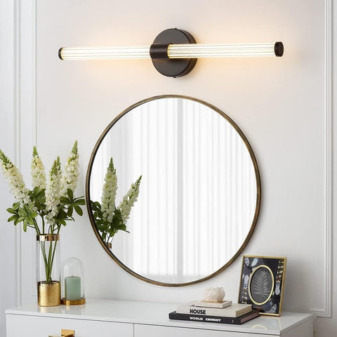 Round mirror with a modern wall light fixture on a white wall.