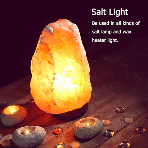 Salt lamp on a wooden surface with candles and water droplets, glowing warmly.