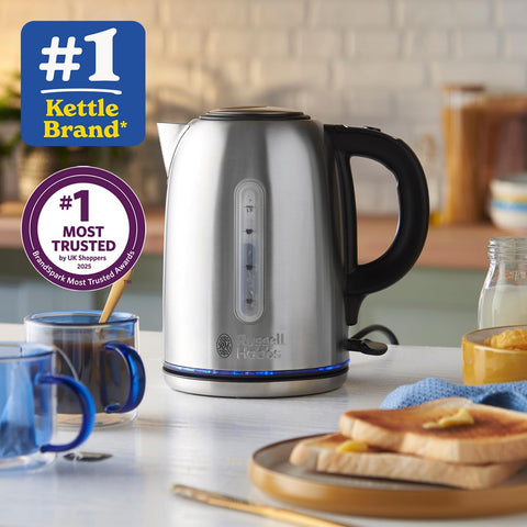 Silver kettle on a kitchen counter with toast and mugs, featuring Russell Hobbs branding.