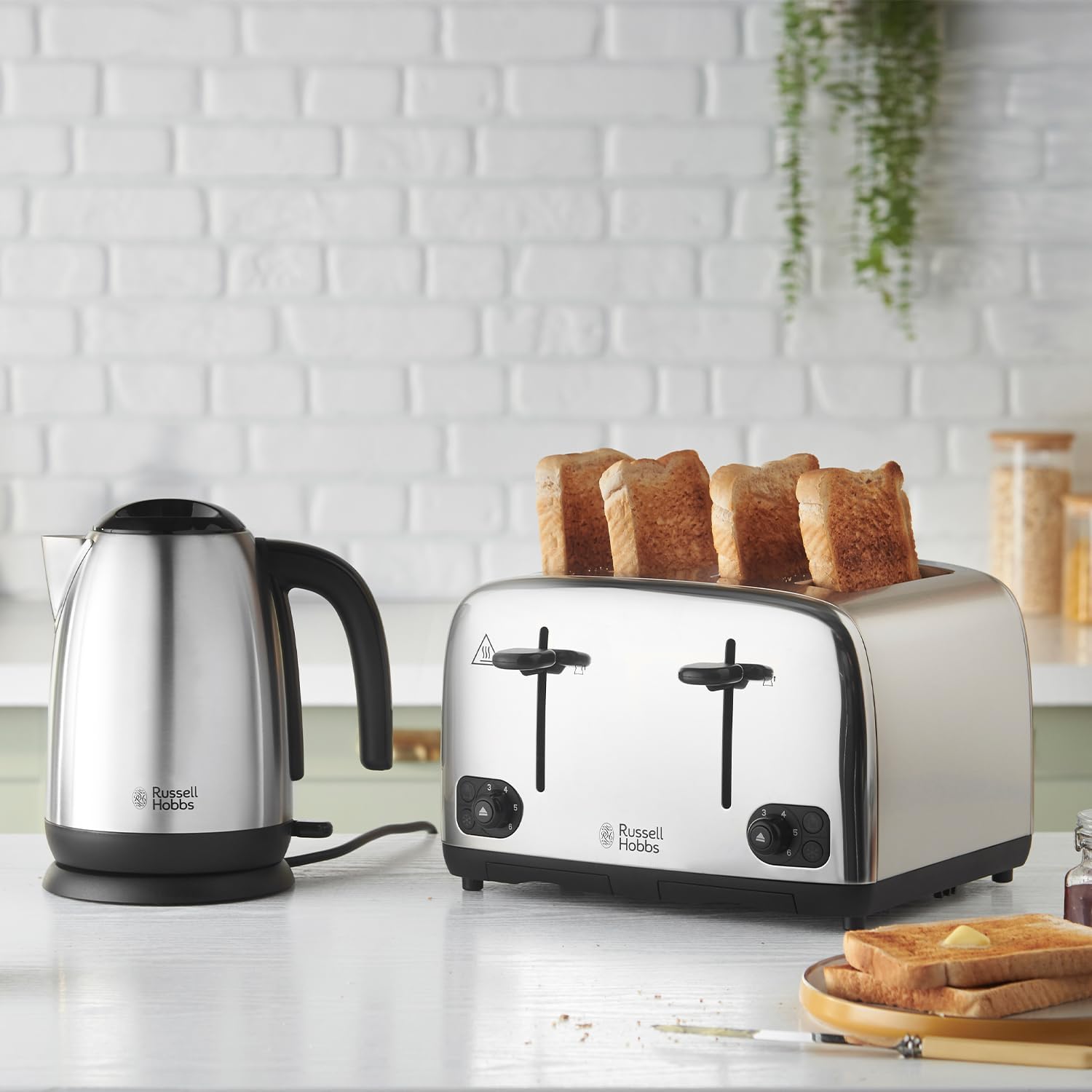Silver toaster with slices of bread and a black and silver kettle on a kitchen counter.