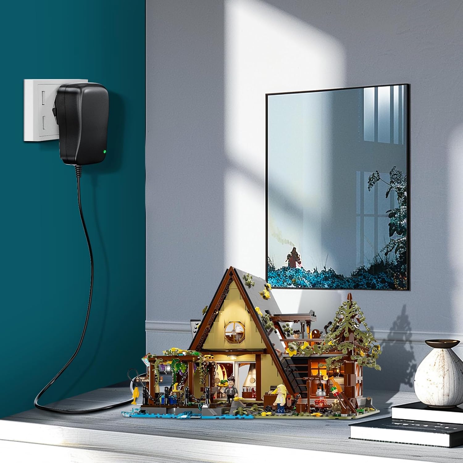 Small model house on a table with a wall outlet and framed picture in the background